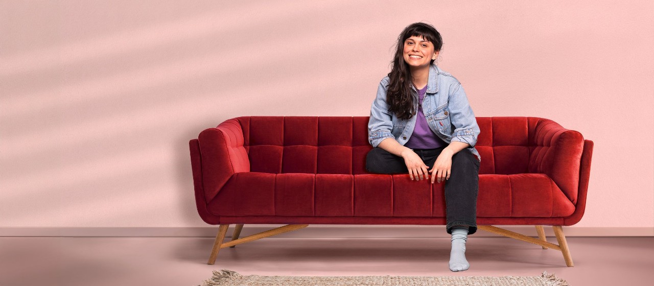 Junge Frau sitzt auf einer roten Couch